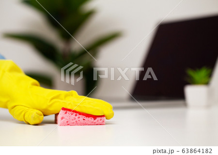 Close up of worker hand wiping dust in office in yellow gloves 63864182