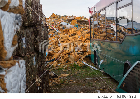 Abandoned city bus in a junkyard close to a orange insulating foam mountain Abandoned city bus in a junkyard close to a orange insulating foam mountain 63864833