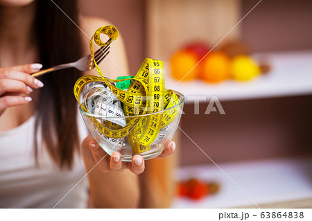 Girl holding a transparent plate full of measuring tape Girl holding a transparent plate full of measuring tape 63864838