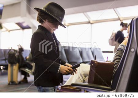 A young boy looking at his briefcase in airport A young boy looking at his briefcase in airport 63869775