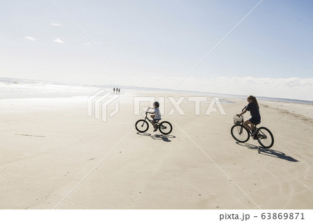 Two children cycling on an open beach, a boy and girl. 63869871