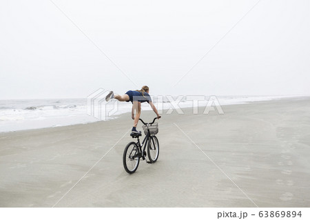 A teenage girl biking on a sandy beach by the ocean A teenage girl biking on a sandy beach by the ocean 63869894