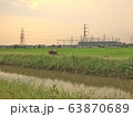 A Man driving motorcycles along the canal road through fields 63870689