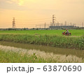 A Man driving motorcycles along the canal road through fields 63870690