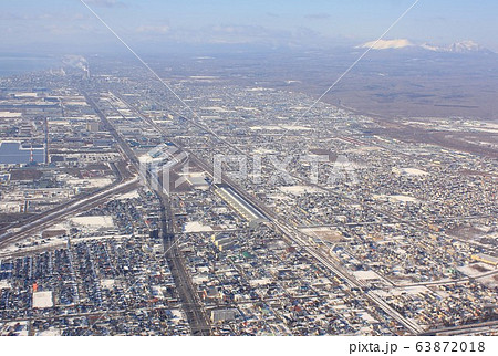 厳冬の北海道、樽前山、風不死岳の連山を背景に道南の港町、苫小牧市街地を上空から見る 63872018