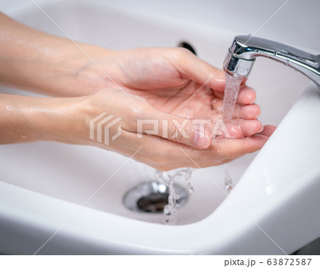 Woman washing hand with tap water in bathroom. 63872587