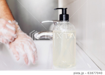 Man cleaning his hands using liquid disinfectant soap. 63877040
