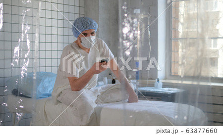 Isolated person in madical mask using his phone in a hospital. 63877660