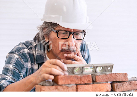 Old Builder craftman is leveling brick wall in 63878632