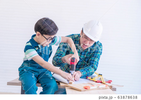 Father and son is drilling wood on workshop table Father and son is drilling wood on workshop table 63878638