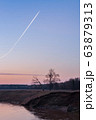 Morning sky with airplane track above the river 63879313