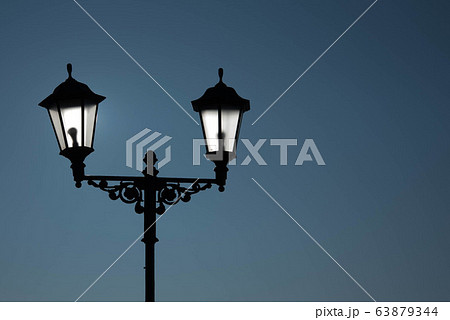Urban landscape. Street lamp with a lamp in a classic style against a purple sky. Beautiful postcard. 63879344