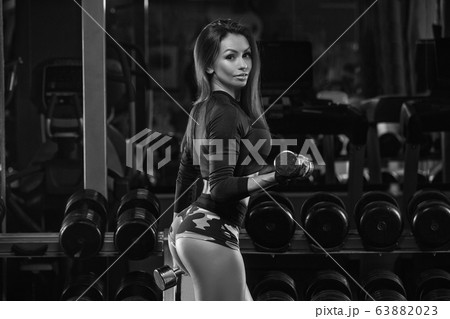 Sportive young woman in a gym training. Working out in a fitness gym. Sportive young woman in a gym training. Working out in a fitness gym. 63882023