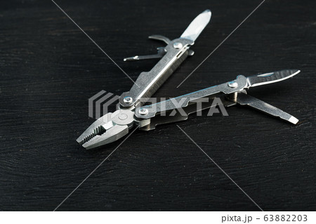Multitool is a multi-functional tool on a black Multitool is a multi-functional tool on a black 63882203
