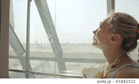 Woman caucasian at airport with wearing protective medical mask on head against the background of the plane. Coronavirus sars-cov-2 covid-19. Woman caucasian at airport with wearing protective medical mask on head against the background of the plane. Coronavirus sars-cov-2 covid-19. 63882522