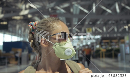 Woman caucasian at airport with wearing protective medical mask on head against the background of the plane. Coronavirus sars-cov-2 covid-19. Woman caucasian at airport with wearing protective medical mask on head against the background of the plane. Coronavirus sars-cov-2 covid-19. 63882523