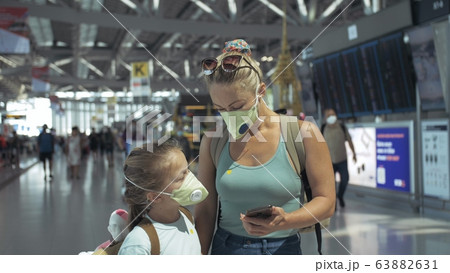 Woman and child baby tourist caucasian at airport with wearing protective medical mask. Family in quarantine isolation. Coronavirus covid-19. 63882631