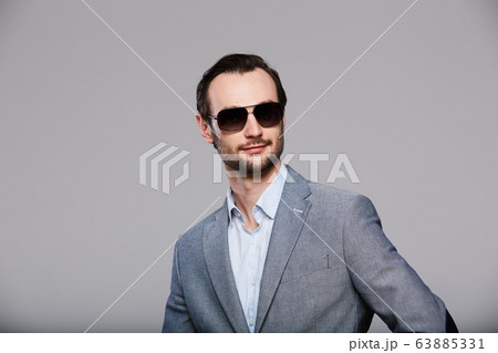 Elegant young handsome man in sunglassesand in stylish gray jacket. Studio fashion portrait. Elegant young handsome man in sunglassesand in stylish gray jacket. Studio fashion portrait. 63885331