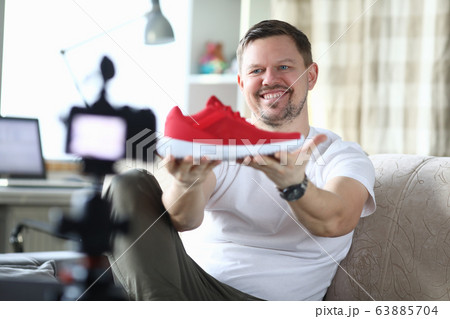 Man in an apartment is filming review new sneakers 63885704