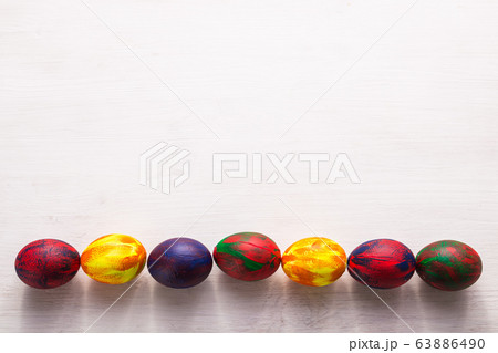 Holidays, traditions and Easter concept - Multi-colored decorative colourful eggs on white background with copy space. Top view. Holidays, traditions and Easter concept - Multi-colored decorative colourful eggs on white background with copy space. Top view. 63886490