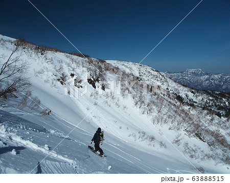 雪の栂池自然園へ滑走するボーダーと遠望の山々 63888515