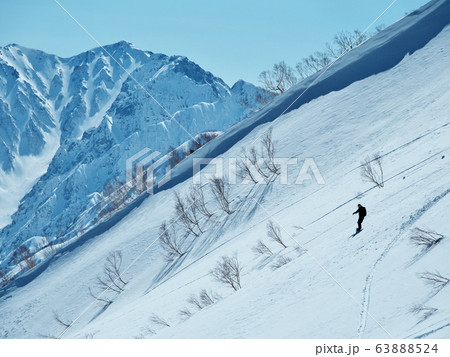 後立山連峰と雪庇を背景に滑走するボーダー 63888524