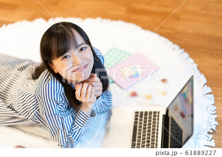 リビングで横になりながら、お菓子を食べる若い女性 63889227