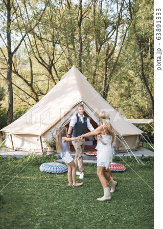 Happy family: mother, father, two children daughters on nature on sunset, dancing and having fun. Boho style, wigwam on the background 63891333