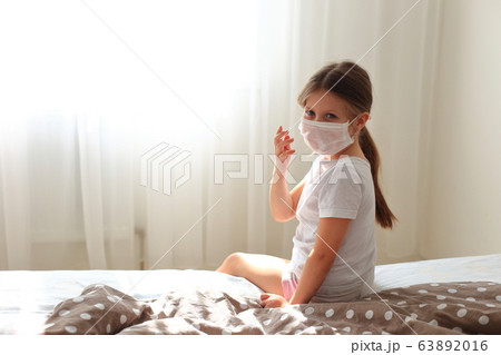 Girl in a respiratory mask sits in quarantine at home. Girl in a respiratory mask sits in quarantine at home. 63892016