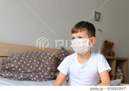 A boy in a respiratory mask sits in quarantine at home A boy in a respiratory mask sits in quarantine at home 63892047