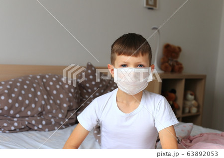 A boy in a respiratory mask sits in quarantine at home A boy in a respiratory mask sits in quarantine at home 63892053