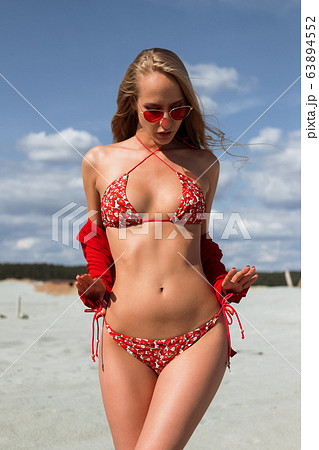 Trendy woman in bright swimwear touching hair at Trendy woman in bright swimwear touching hair at 63894552
