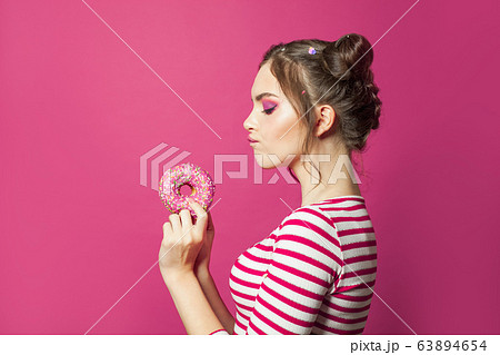 Attractive woman holding donut on vivid pink Attractive woman holding donut on vivid pink 63894654