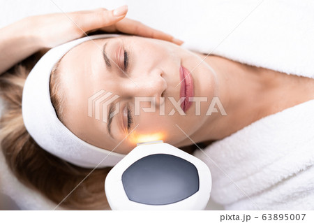 Beautician performing photorejuvenation procedure Beautician performing photorejuvenation procedure 63895007