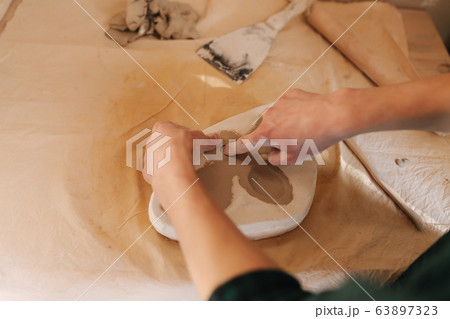 Stamp on clay, butterfly. Ceramic product. Hand of man on the table Stamp on clay, butterfly. Ceramic product. Hand of man on the table 63897323