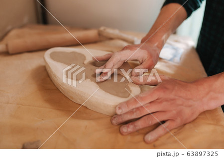 Hands of potter fill the form with a ceramic in the shape of a butterfly. Close up of hands Hands of potter fill the form with a ceramic in the shape of a butterfly. Close up of hands 63897325