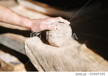 Close up of man works with clay. Male potter kneads and moistens the clay before work, toned Close up of man works with clay. Male potter kneads and moistens the clay before work, toned 63897395