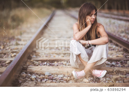 Sad young woman sitting on the railway. 63898294