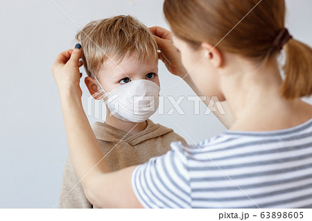 Mother putting on medical mask on son. 63898605