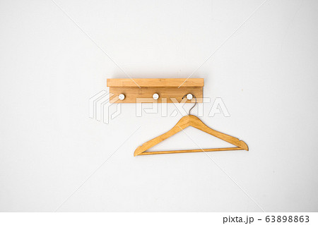 Clothes wooden hanger on a white wall. Clothes wooden hanger on a white wall. 63898863