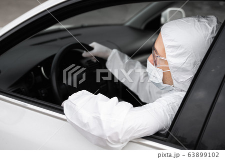 Man in protective suit, medical mask and rubber gloves for protect from bacteria and virus is planning to drive. Protective mask while quarantine, world pandemic, covid 19, coronavirus, infection. Man in protective suit, medical mask and rubber gloves for protect from bacteria and virus is planning to drive. Protective mask while quarantine, world pandemic, covid 19, coronavirus, infection. 63899102