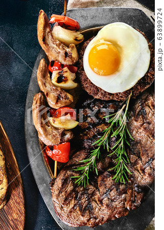 Grilled meat platter on a plate with grilled vegetables, grilled meat. Food photo, dark background 63899724