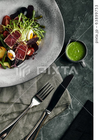 Nicoise salad with tuna on a gray plate, on a serving table. A beautiful dish from the chef, food photo, gray background, copy space, traditional French cuisine. 63899753