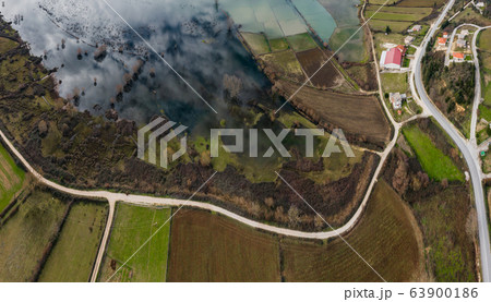 Flight over the flooded valley in Greece. The flooded fields, roads, mountains on background, the inhabited settlement. Reflection of mountains in water 63900186