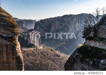 Aerial view of monastery Rousanou and breathtaking picturesque valley and landmark canyon of Meteora at sunset, Kalambaka, Greece, shadows, twisted road, bridge 63900271