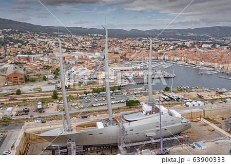 Aerial view of sea dry dock in La Ciotat city, France, the cargo crane, boats on repair, a luxury sail yacht and motor yacht, mountain is on background, shipyard Aerial view of sea dry dock in La Ciotat city, France, the cargo crane, boats on repair, a luxury sail yacht and motor yacht, mountain is on background, shipyard 63900333