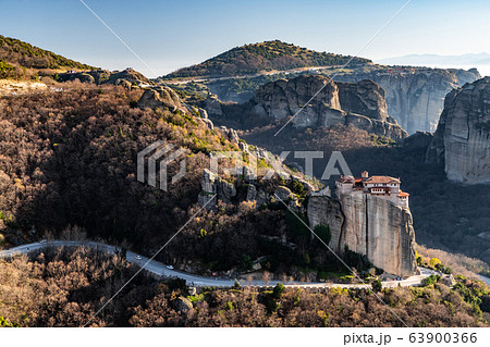 Aerial view of monastery Rousanou and breathtaking picturesque valley and landmark canyon of Meteora at sunset, Kalambaka, Greece, shadows, twisted road, bridge Aerial view of monastery Rousanou and breathtaking picturesque valley and landmark canyon of Meteora at sunset, Kalambaka, Greece, shadows, twisted road, bridge 63900366
