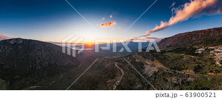 Aerial view of Delphi, Greece, the Gulf of Corinth, orange color of clouds, mountainside with layered hills beyond with rooftops in foreground 63900521