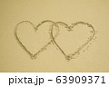 Two hearts drawn on the sand beach representing 63909371
