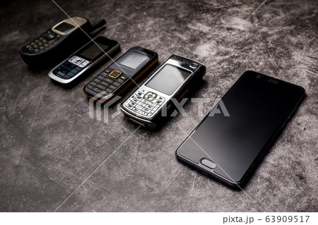 Many obsoleted cellphones and a smartphone on a grunge background. Many obsoleted cellphones and a smartphone on a grunge background. 63909517